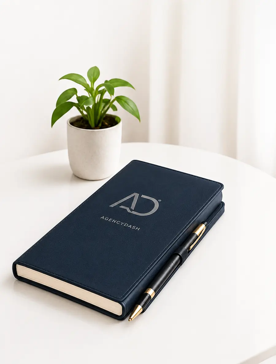 AgencyDash notebook, pen and plant on a bright desk